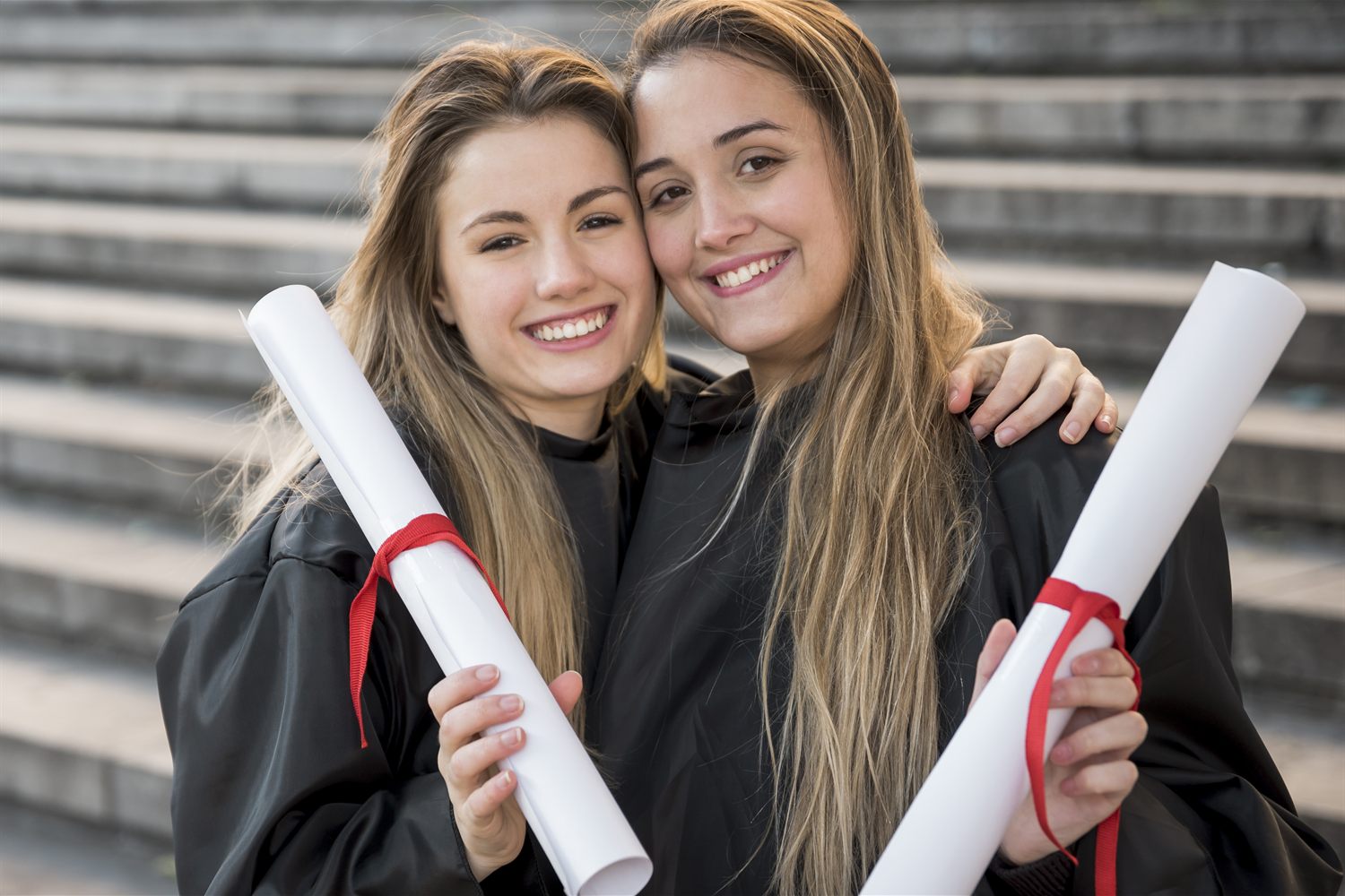 Estudantes sorridentes segurando diplomas universitários